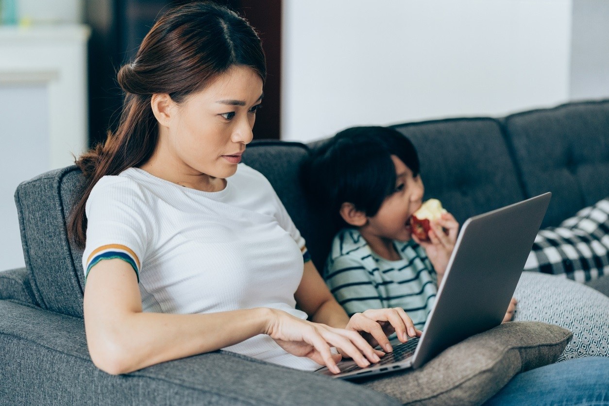 Mother doing Ridiculously Effective Parenting Training course on laptop.